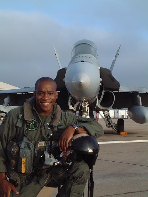 Spektacle Imaging Solutions photographer in Marine Corps flight gear beside a fighter aircraft